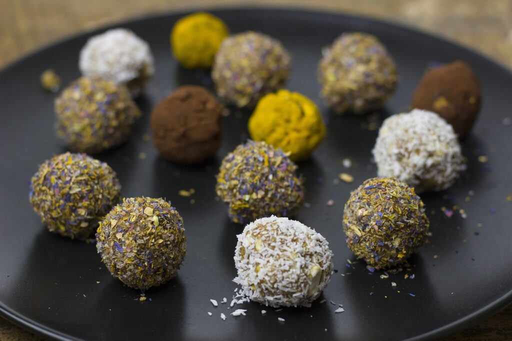 Assortment of colorful and healthy vegan snacks including energy balls, veggie sticks with hummus, and fresh fruit